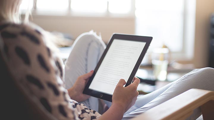 Person auf einem Sofa mit einem Tablet in der Hand