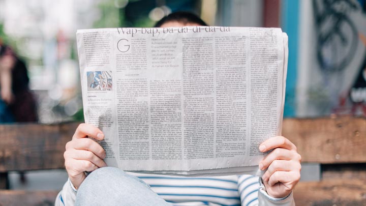 Person auf einer Bank mit einer Zeitung in der Hand